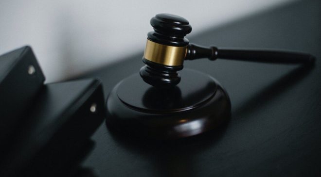 small judge gavel placed on table near folders